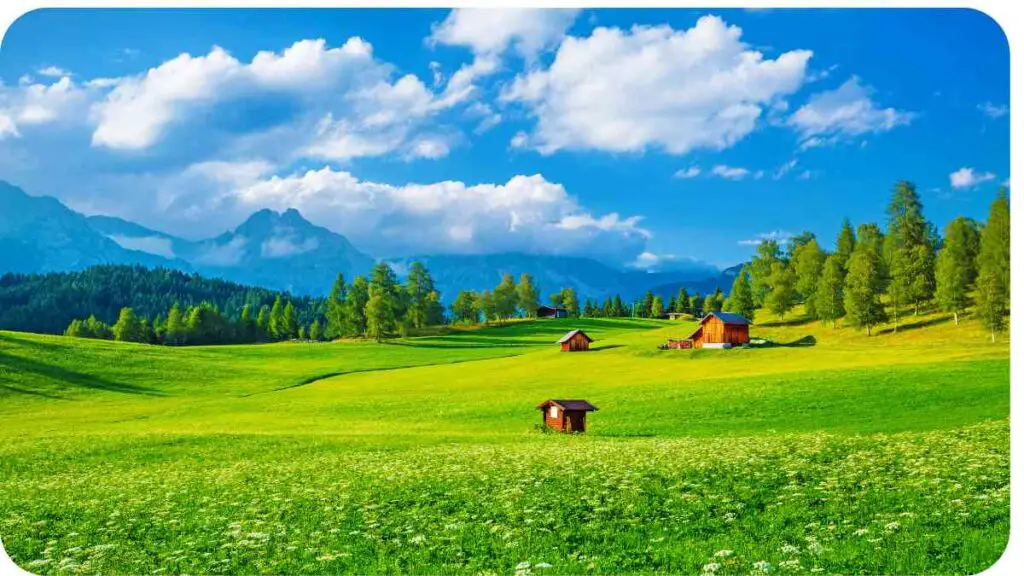 a green field with a house in the middle and a mountain range in the background