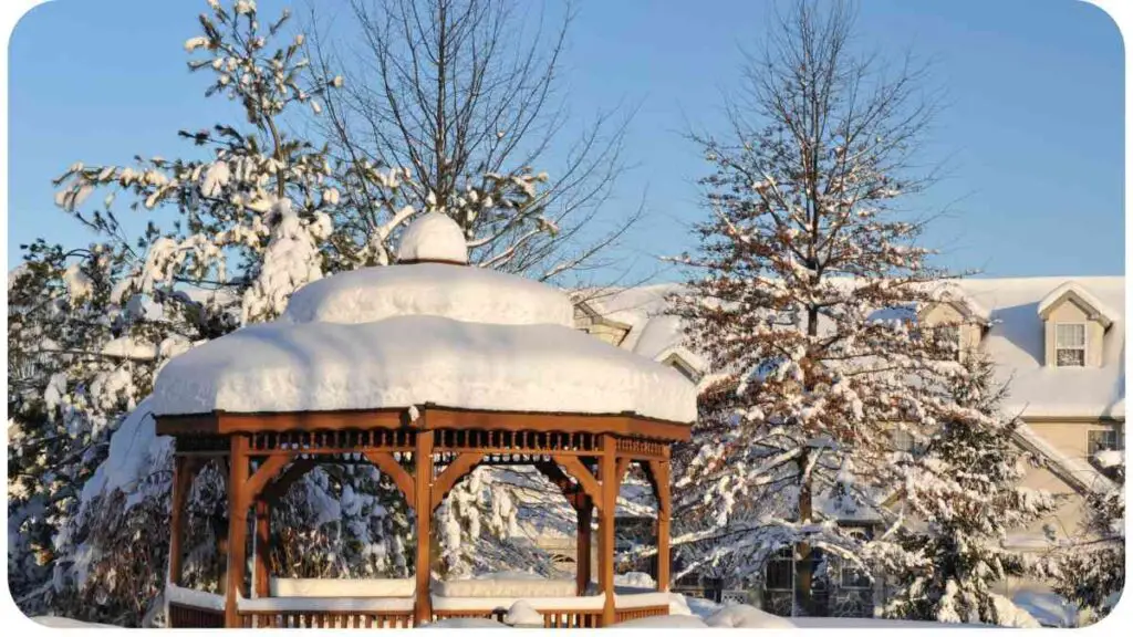 a gazebo covered in snow in front of a house