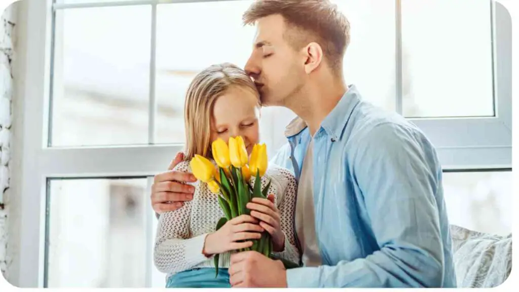 a person is kissing a child as they hold a bunch of yellow tulips