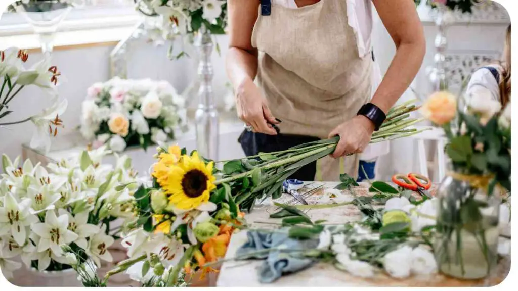 a woman in an apron is working on a flower arrangement