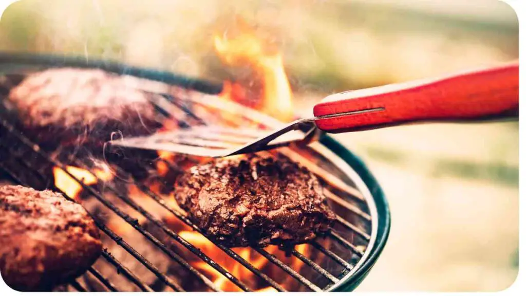 a person holding a spatula over a grill with hamburgers on it