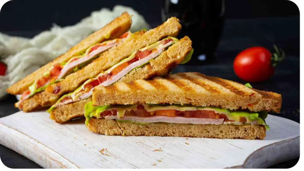 sandwiches on a cutting board with tomatoes