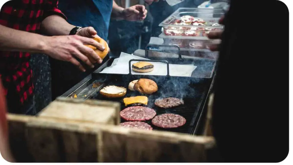 people cooking hamburgers on an outdoor grill