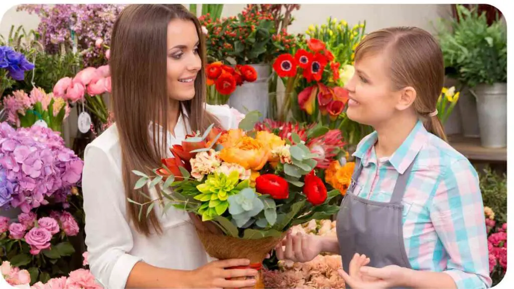 two people are standing in a flower shop and one is holding a bouquet of flowers